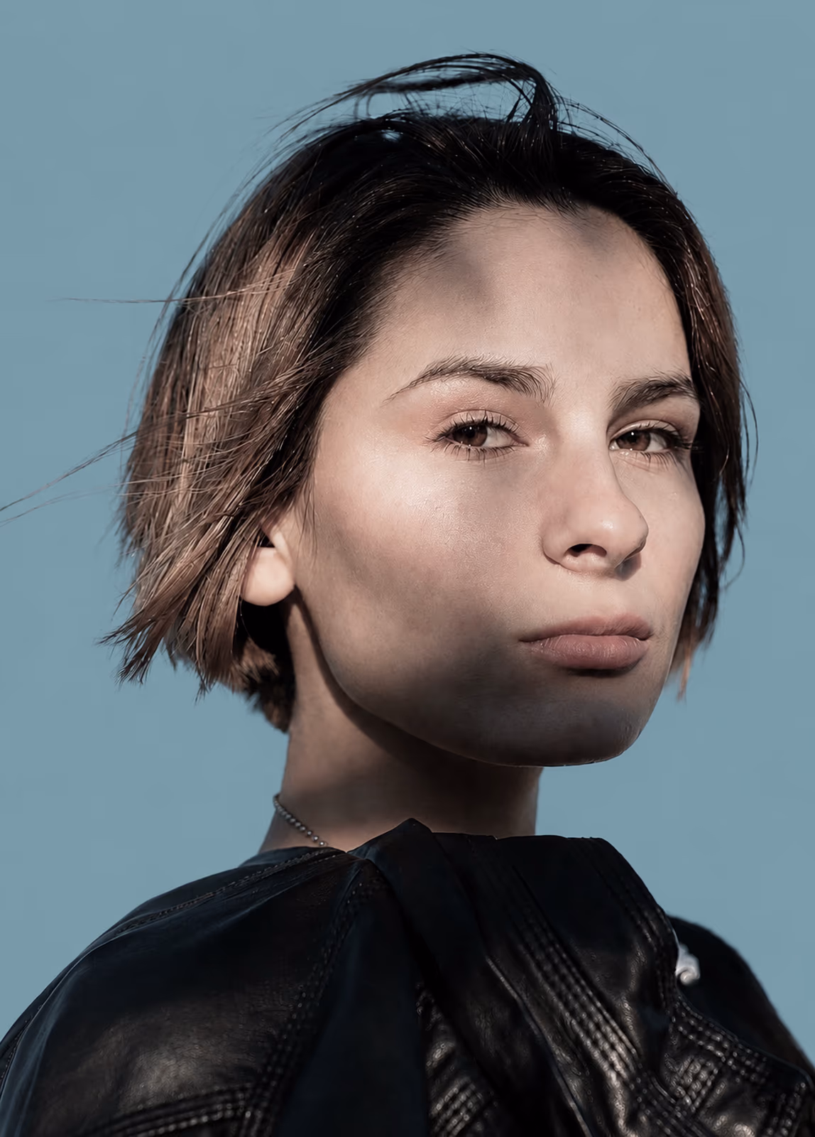 Portrait d’une jeune femme au regard déterminé, sur fond bleu